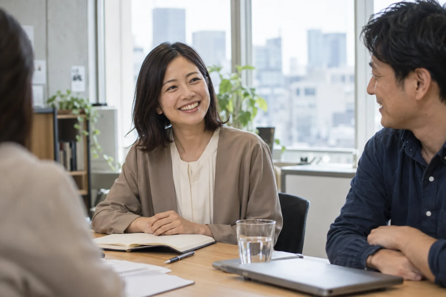 会議で提案が伝わり、同僚と自然に笑顔を交わす女性のイメージ
